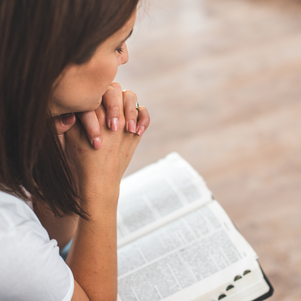 Overcoming fear and self doubt through biblical principles on faith. Image has image of a woman reading the bible and praying.