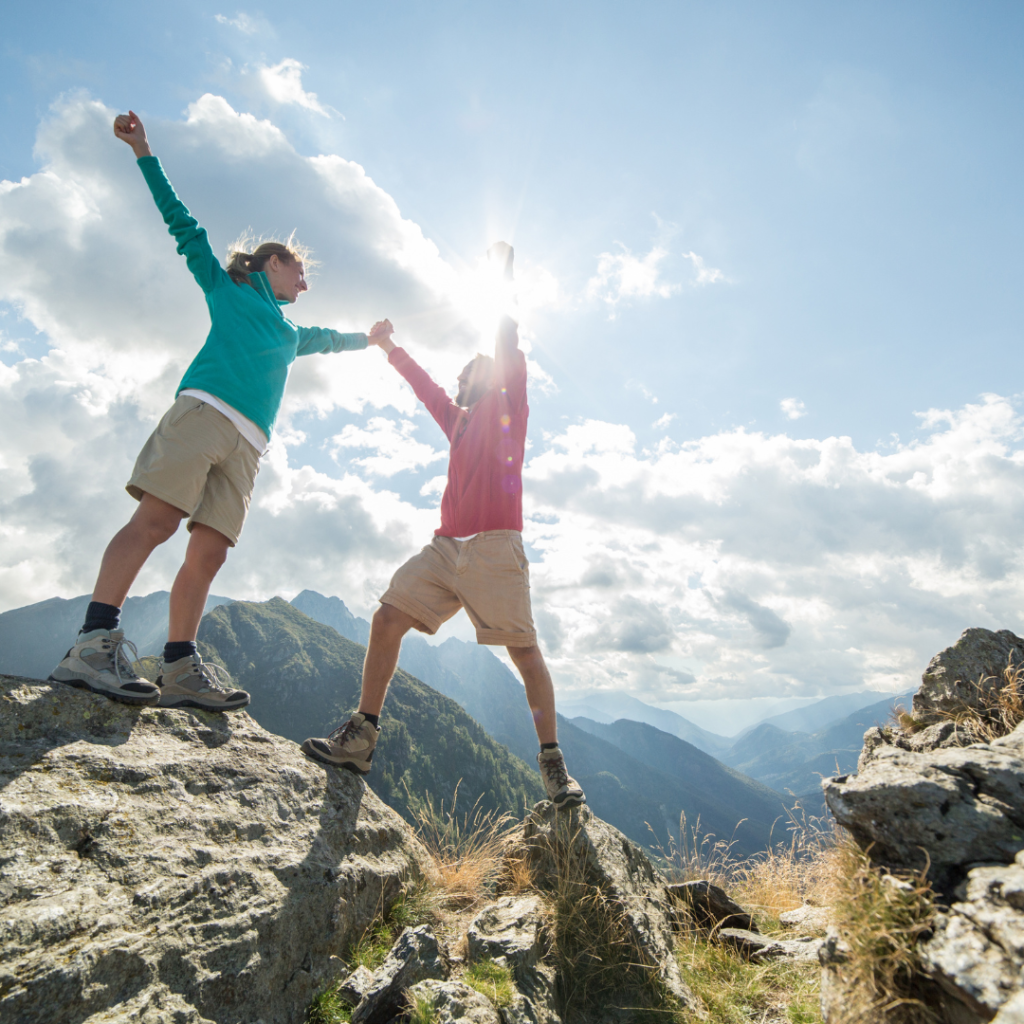 Overcoming fear and self doubt. Image shows two people on top of a mountain being victorious.