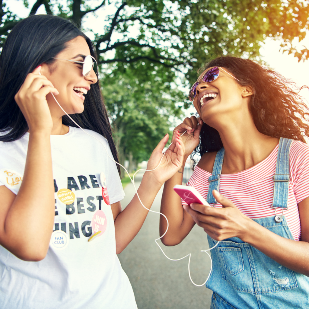 Should Christians Listen to Secular Music? Image is of two friends sharing headphones as they listen to music. 