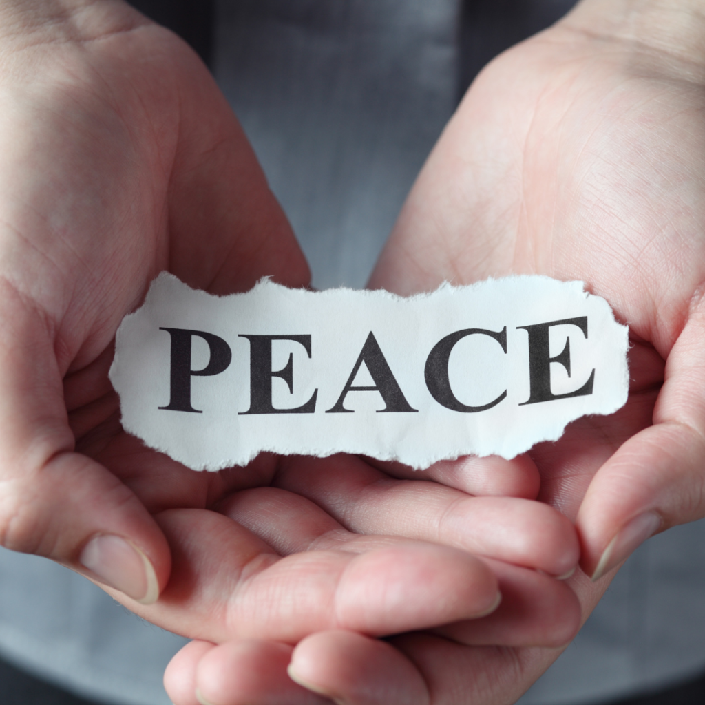 Overcoming fear and self doubt by finding peace through Jesus Christ. This image is of a hand holding a ripped peace of paper with the word "peace" on it.