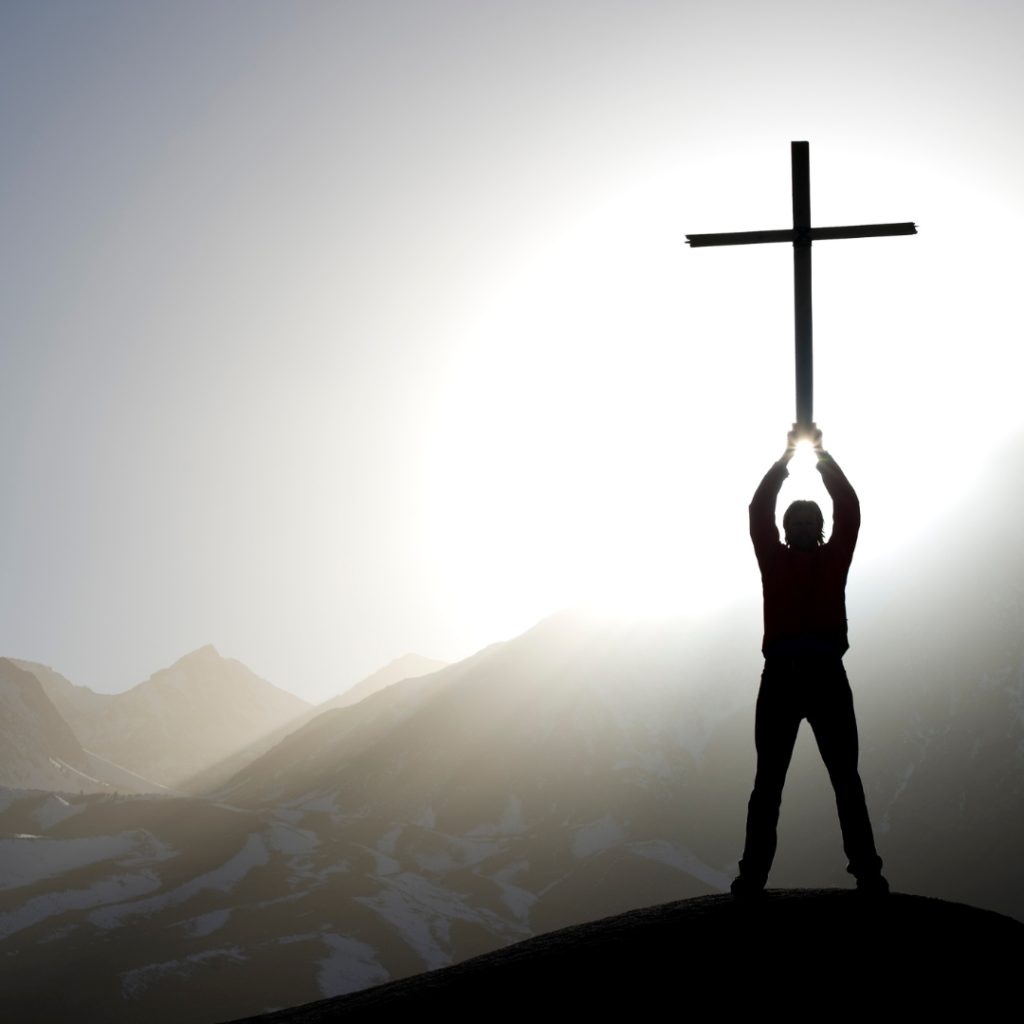 Jesus was our example of strength and going to church. He didn't see going to church as weakness. Image is of a man standing on top of a mountain holding up a cross.