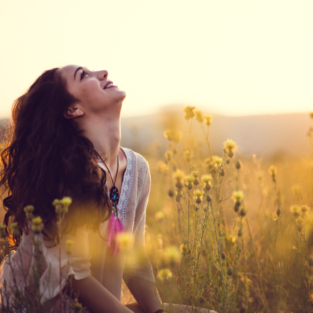 Accepting God's Grace can change the way we view ourselves and how we treat each other. The image is of a woman sitting in a meadow looking at peace. 